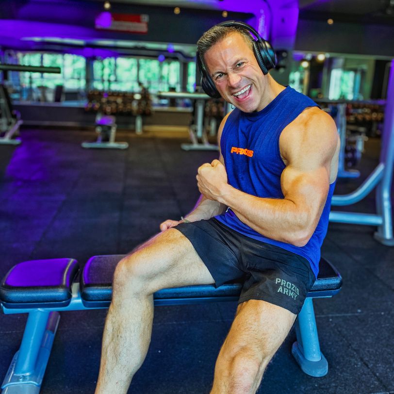 Albert is happy in the gym. He is showing his biceps.